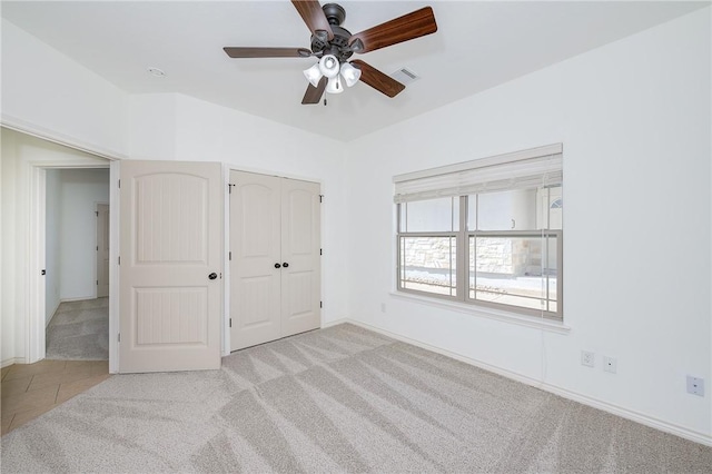 unfurnished bedroom featuring visible vents, baseboards, carpet floors, tile patterned floors, and a ceiling fan