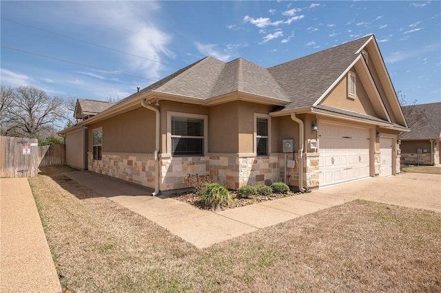 view of front of house featuring fence, roof with shingles, stucco siding, stone siding, and driveway