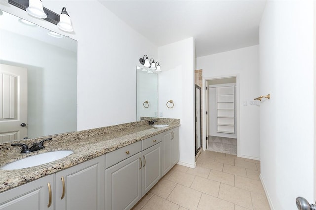 bathroom featuring a sink, a stall shower, double vanity, and tile patterned floors