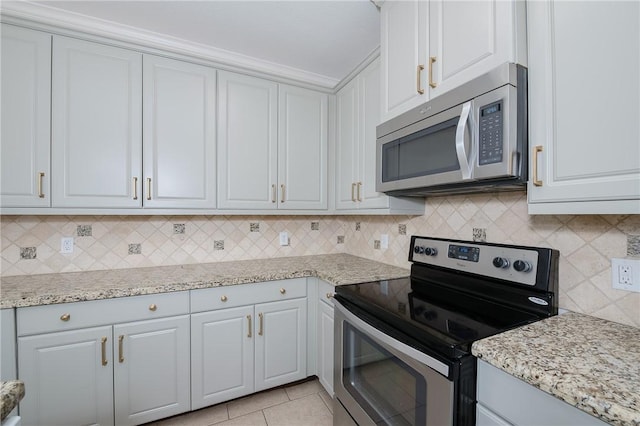 kitchen featuring light stone counters, backsplash, stainless steel appliances, light tile patterned flooring, and white cabinets