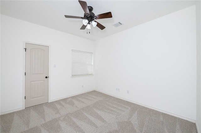 carpeted empty room with visible vents, baseboards, and a ceiling fan