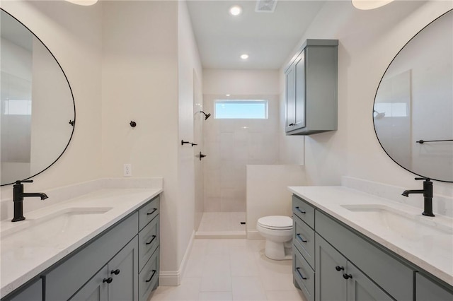 bathroom featuring vanity, a tile shower, tile patterned floors, and toilet