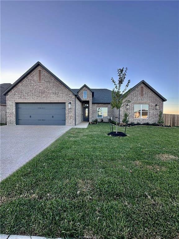 view of front of home with a garage and a lawn