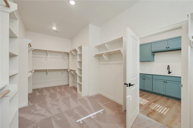 walk in closet with sink and light carpet