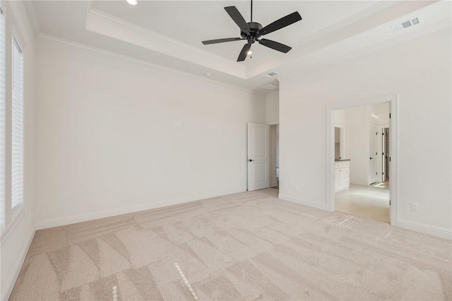 carpeted empty room featuring a raised ceiling, ornamental molding, and ceiling fan