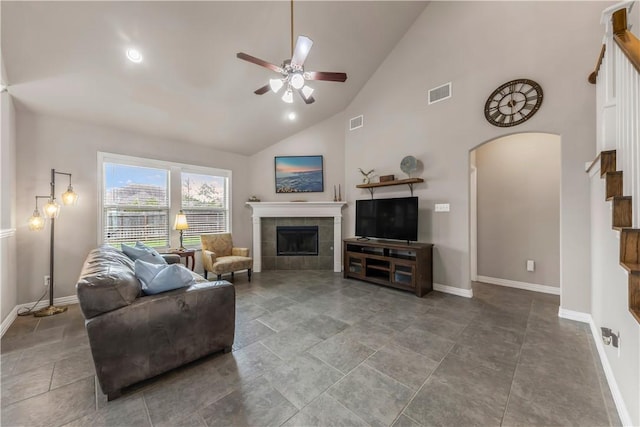 2609 Kimbolton Dr, College Station, TX 77845 - living area with a ceiling fan, a tiled fireplace, arched walkways, baseboards, and high vaulted ceiling