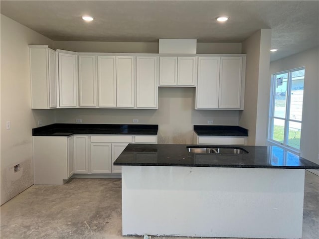 kitchen with a kitchen island, white cabinetry, and dark stone counters