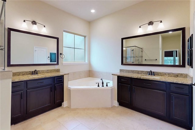 full bath with a garden tub, a shower stall, two vanities, and a sink