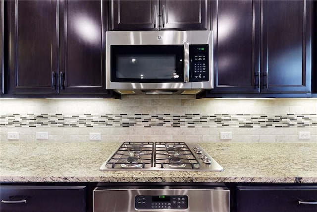 kitchen featuring appliances with stainless steel finishes, light stone countertops, and decorative backsplash