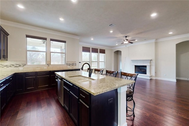 kitchen featuring a center island with sink, a kitchen breakfast bar, a sink, and open floor plan