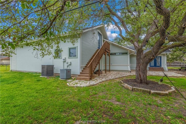 rear view of property with central AC and a yard