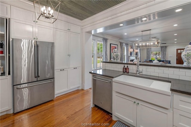 kitchen featuring white cabinetry, pendant lighting, stainless steel appliances, and light hardwood / wood-style flooring