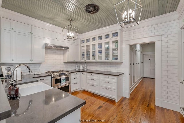 kitchen featuring white cabinets, light hardwood / wood-style flooring, double oven range, and hanging light fixtures