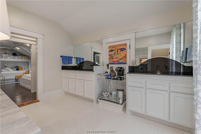 bathroom featuring vanity, wood-type flooring, and lofted ceiling