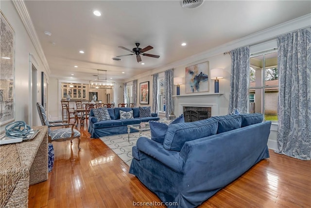 living room with ceiling fan, wood-type flooring, and crown molding