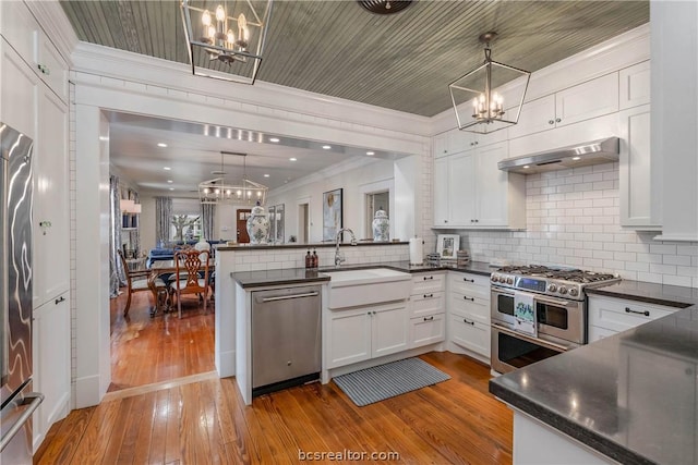 kitchen featuring light hardwood / wood-style floors, decorative light fixtures, and appliances with stainless steel finishes