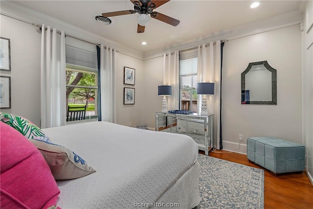 bedroom featuring hardwood / wood-style floors, ceiling fan, crown molding, and multiple windows