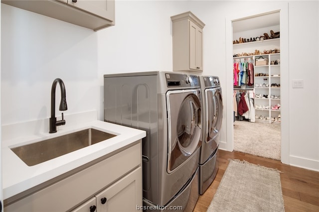 laundry room with cabinets, independent washer and dryer, light wood-type flooring, and sink