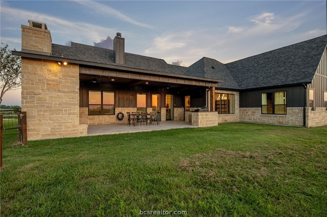 back house at dusk with a yard and a patio