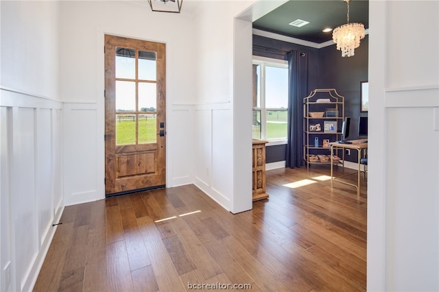 foyer with a chandelier, plenty of natural light, hardwood / wood-style floors, and ornamental molding