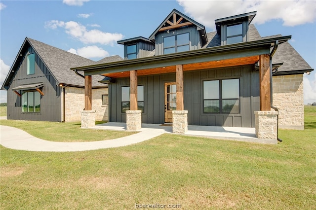 rear view of property featuring a lawn and covered porch