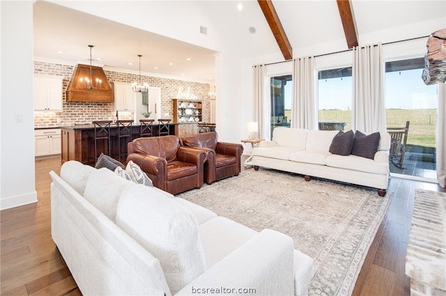 living room featuring lofted ceiling with beams, light hardwood / wood-style floors, and brick wall