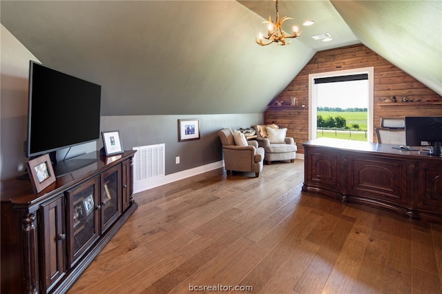 office space featuring wooden walls, light hardwood / wood-style floors, vaulted ceiling, and an inviting chandelier