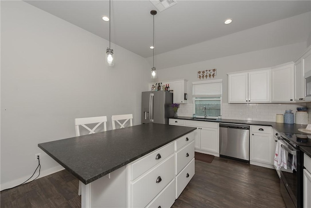 kitchen with tasteful backsplash, stainless steel appliances, white cabinets, a center island, and hanging light fixtures