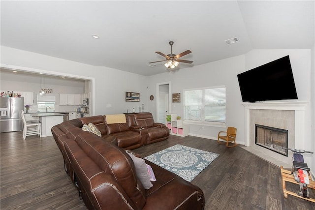 living room with dark hardwood / wood-style flooring, vaulted ceiling, ceiling fan, sink, and a fireplace