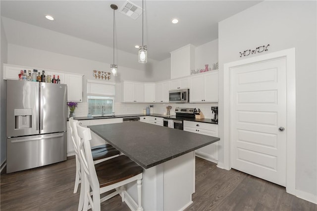 kitchen with backsplash, stainless steel appliances, sink, white cabinets, and a center island