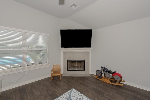 living room with a tile fireplace, dark hardwood / wood-style floors, and lofted ceiling