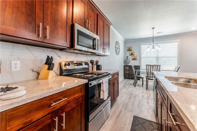 kitchen with ornamental molding, light stone countertops, and appliances with stainless steel finishes