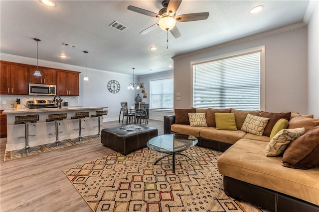 living room with ornamental molding, ceiling fan, and light wood-type flooring