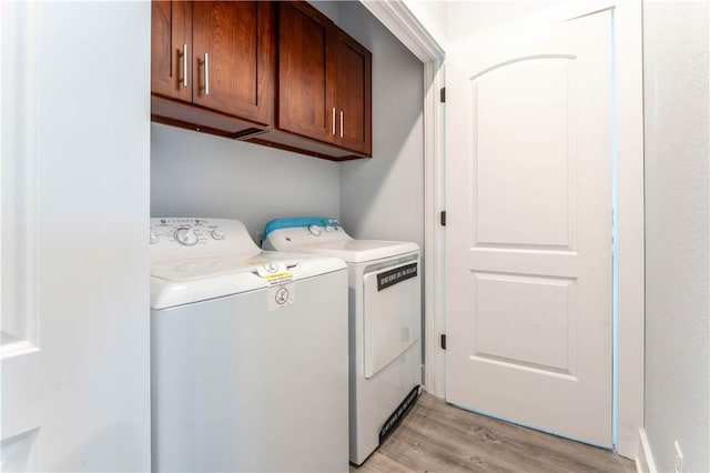 laundry room featuring cabinets, independent washer and dryer, and light hardwood / wood-style floors