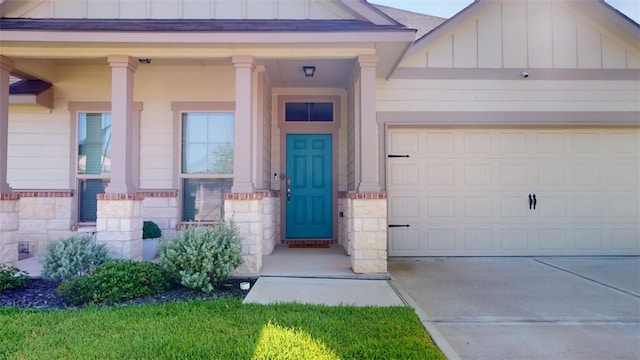 1924 Cartwright St, Bryan, TX 77807 - view of exterior entry featuring board and batten siding, driveway, a garage, and stone siding