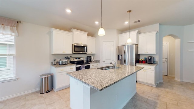 1924 Cartwright St, Bryan, TX 77807 - kitchen featuring appliances with stainless steel finishes, a sink, arched walkways, a kitchen island with sink, and white cabinetry