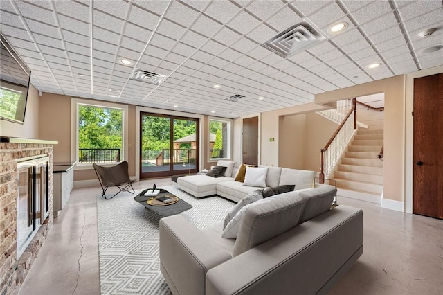 4727 Johnson Creek Loop, College Station, TX 77845 - living area featuring a glass covered fireplace, finished concrete floors, plenty of natural light, and a drop ceiling