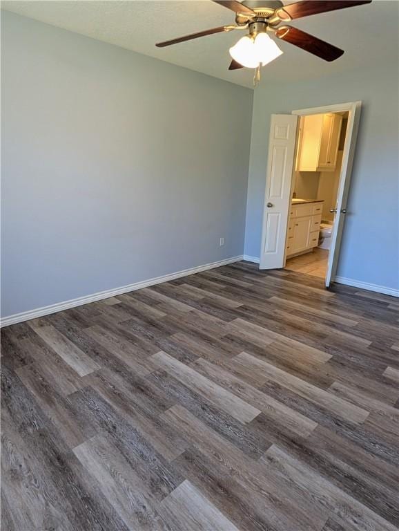 unfurnished bedroom featuring ceiling fan, ensuite bathroom, and dark hardwood / wood-style floors