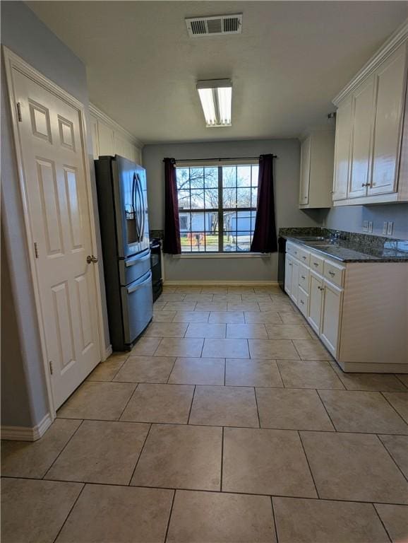 kitchen featuring stainless steel refrigerator with ice dispenser, sink, light tile patterned flooring, and white cabinets