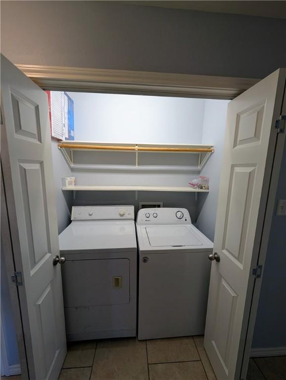 clothes washing area featuring light tile patterned flooring and washer and clothes dryer