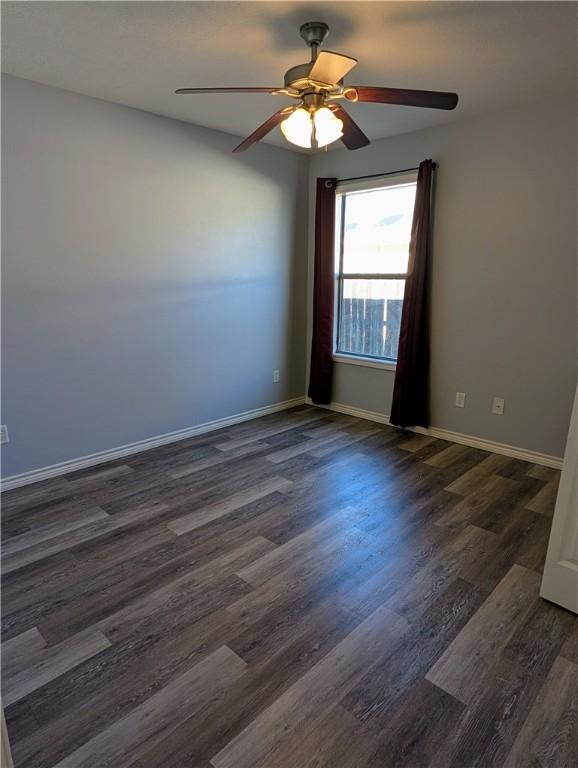 unfurnished room with dark wood-type flooring and ceiling fan