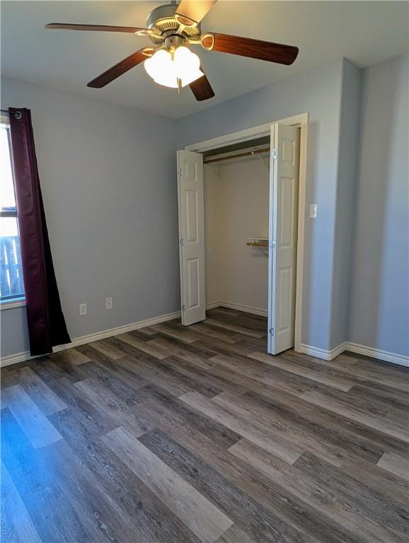 unfurnished bedroom with ceiling fan, dark hardwood / wood-style flooring, and a closet