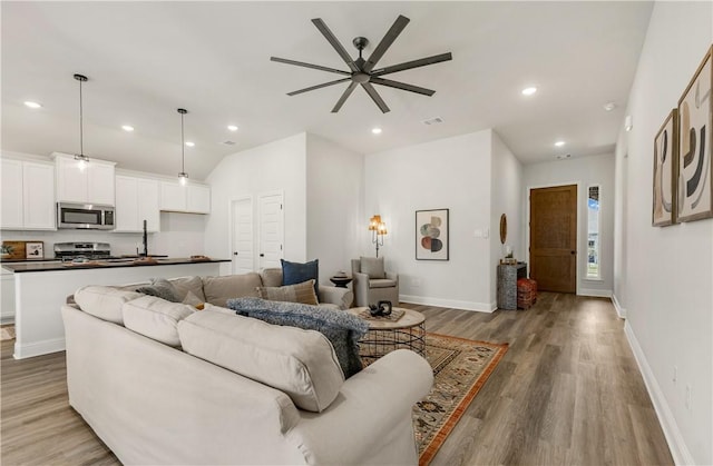 living room with light wood-type flooring, ceiling fan, and lofted ceiling