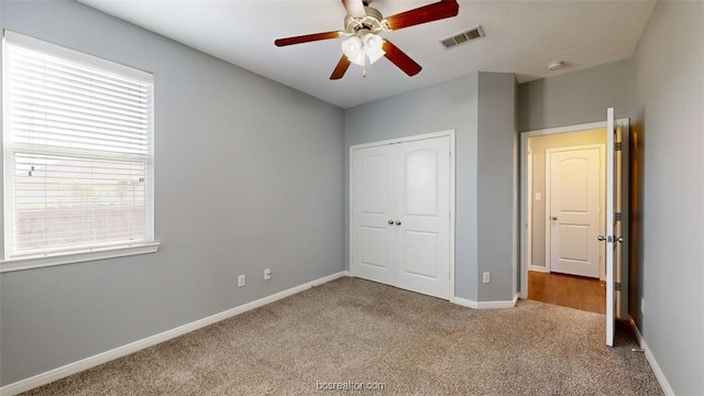 unfurnished bedroom with ceiling fan, multiple windows, a closet, and carpet