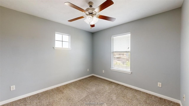 carpeted spare room featuring ceiling fan and plenty of natural light