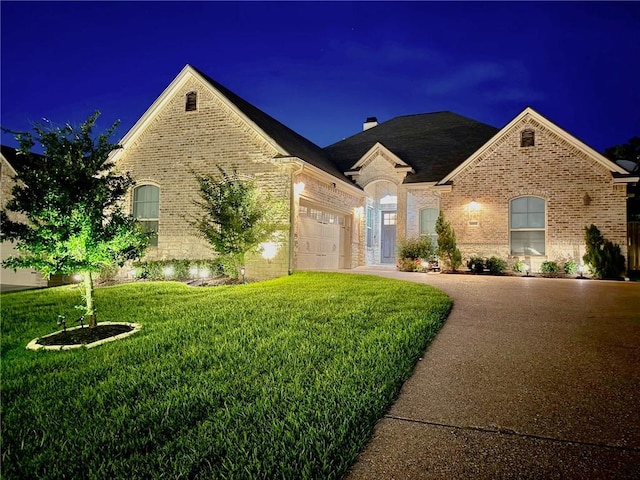 3204 Ashville Path, Bryan, TX 77808 - french country style house featuring brick siding, an attached garage, a front yard, a chimney, and driveway