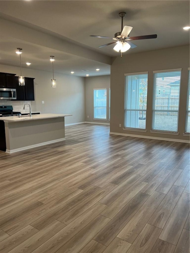 unfurnished living room featuring sink, hardwood / wood-style floors, and ceiling fan