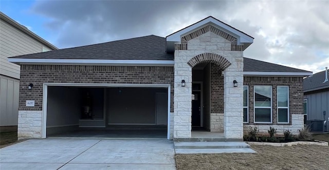 view of front of house with a garage and central air condition unit