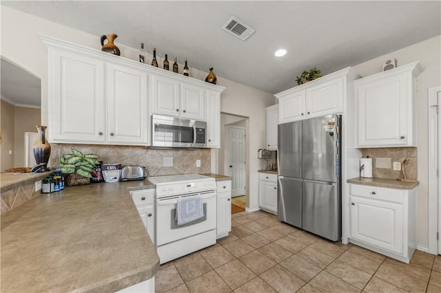 kitchen with backsplash, white cabinets, light tile patterned floors, and appliances with stainless steel finishes