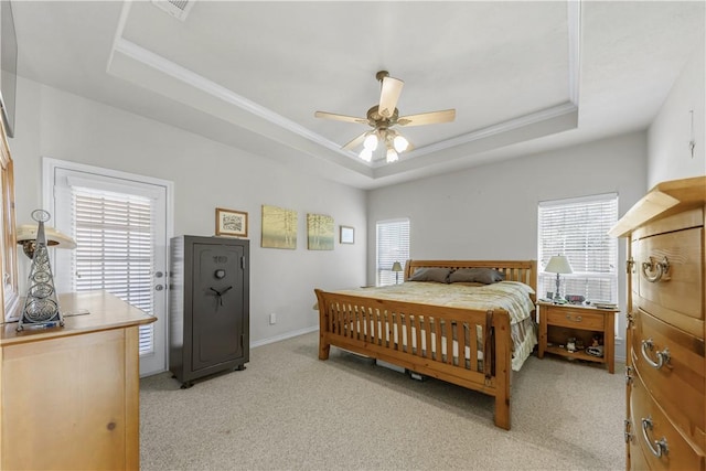 bedroom with a tray ceiling, ceiling fan, crown molding, and light carpet